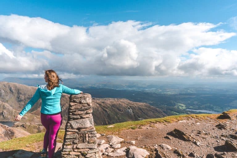 Helen stood at the summit of the Old Man of Coniston overlooking the surrounding mountainscapes in the things to do in the Lake District, England
