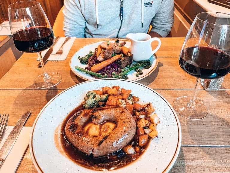 A cosy pub lunch in Windermere is one of the best things to do in the Lake District with some lamb and a Cumberland sausage