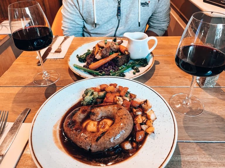 A cosy pub lunch in Windermere is one of the best things to do in the Lake District with some lamb and a Cumberland sausage, England