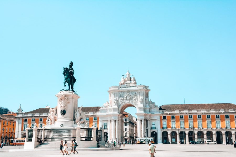 The grand Praça do Comércio with a large arch and yellow buildings, places you must see in Lisbon, Portugal