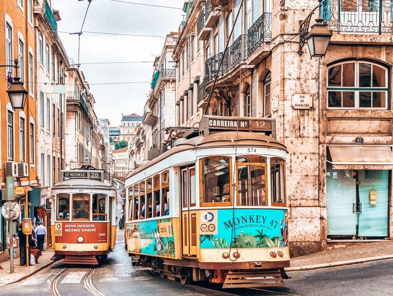 Two yellow trams on the quaint streets on Lisbon in between old buildings