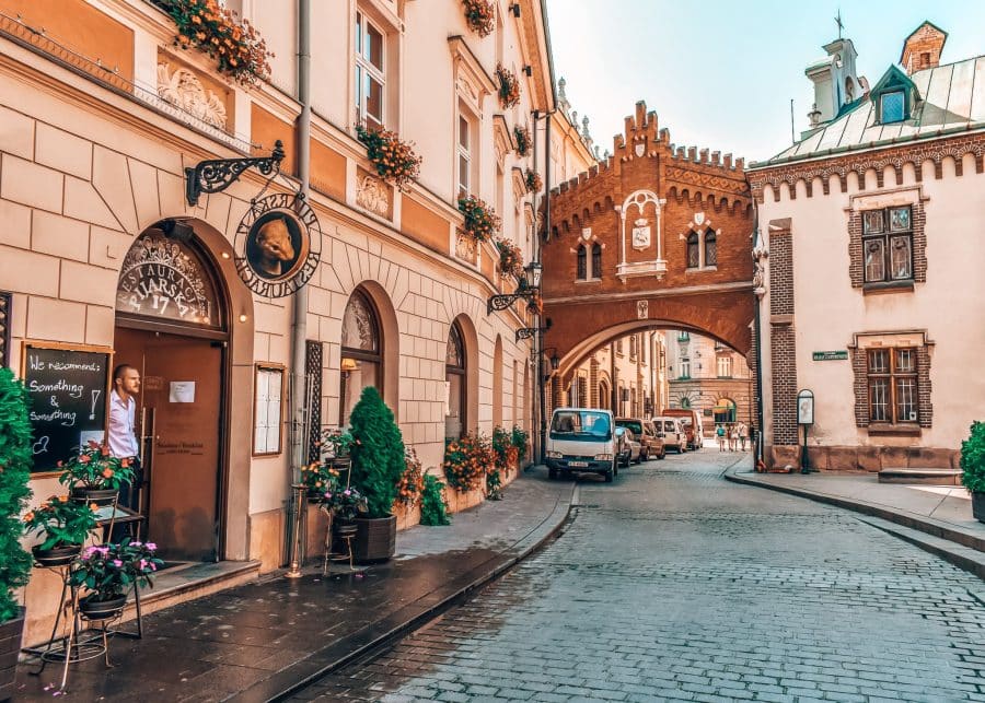 A quaint cobbled street with ancient archway over the road, places to visit in Krakow Old Town, Poland