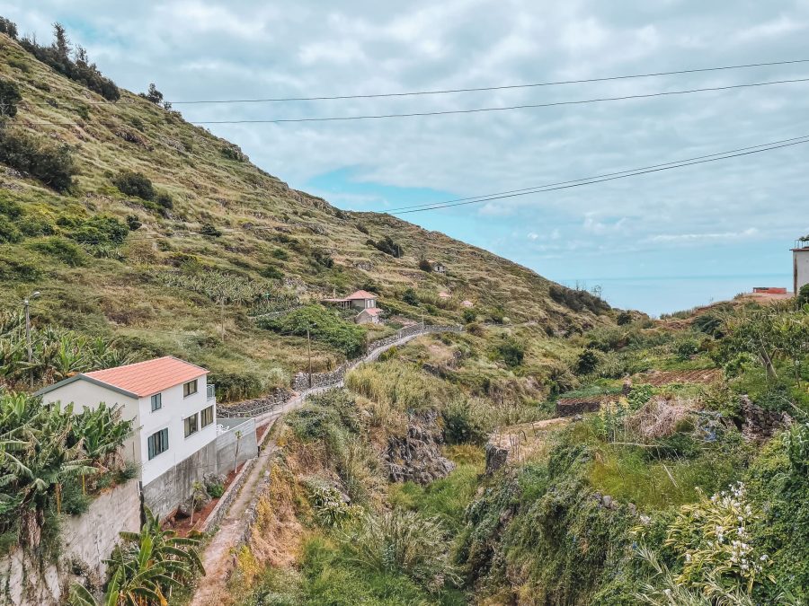 View from the road across the start of the path to Calhau da Lapa. Flat and luscious green with the ocean in the background. Places in Madeira, Portugal