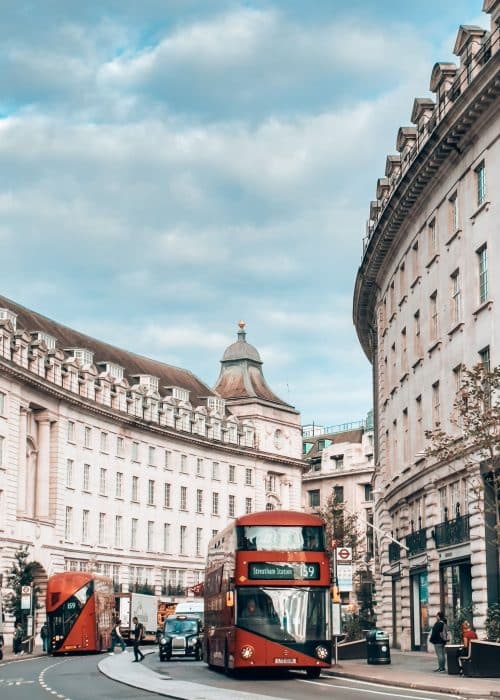 The grand and historical buildings of Regent Street with a red bus going in each direction down it, London