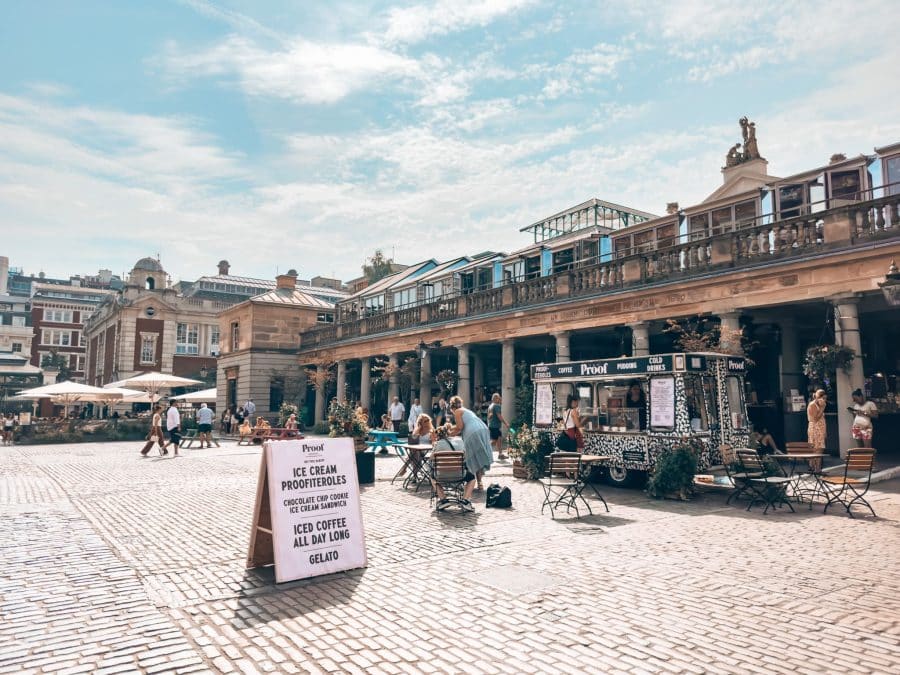 Market stalls and cafes line Covent Garden's piazza on s sunny afternoon on a weekend in London