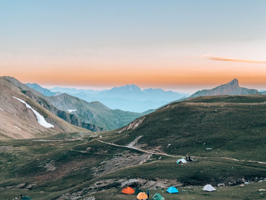 Tents underneath Refuge du col de la Croix du Bonhomme at sunrise with the golden sky on the TMB French Alps, France