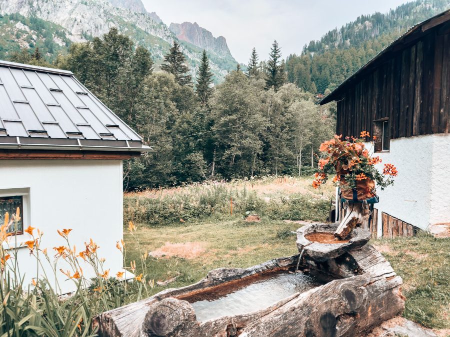 A water trough decorated with flowers at the Gîte du Moulin with a beautiful mountain backdrop, Tour du Mont Blanc, Argentière, Chamonix, France