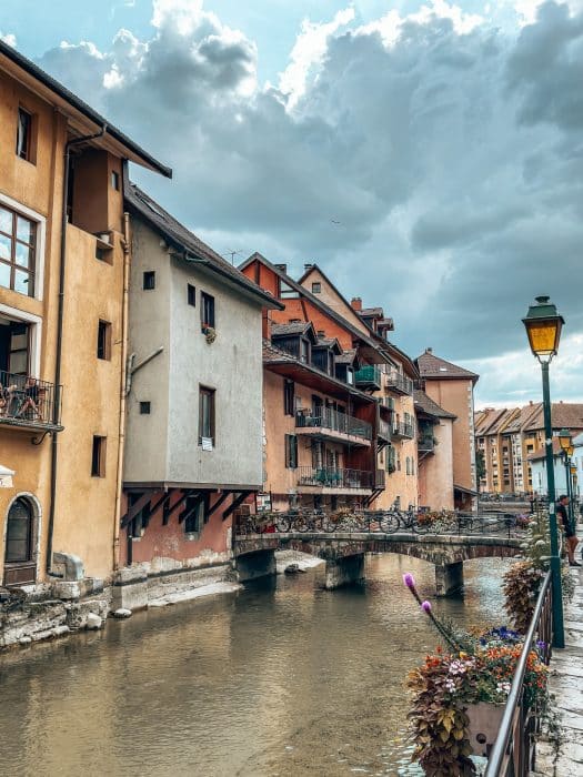 Colourful historical buildings line Le Thiou as a quaint bridge crosses it, Annecy Old Town, France