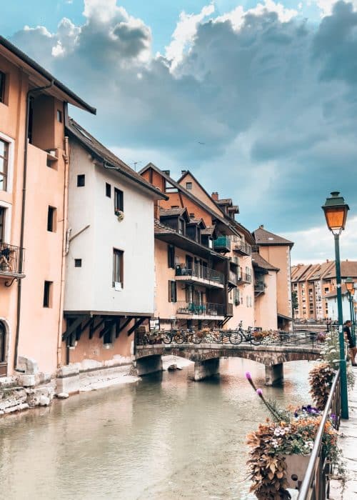 Colourful historical buildings line the Thiou River's canals as a quaint bridge crosses it, Annecy Old Town, France