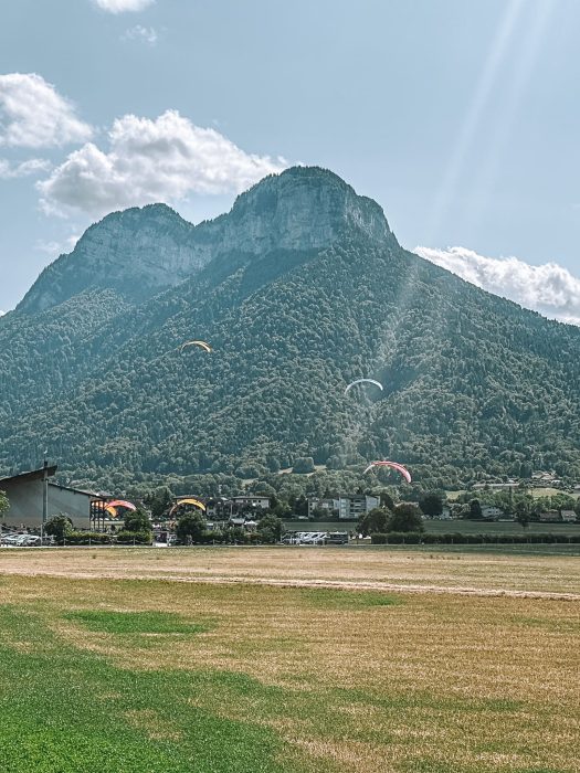 Paragliders landing in the mountainous countryside surrounding Lake Annecy, France