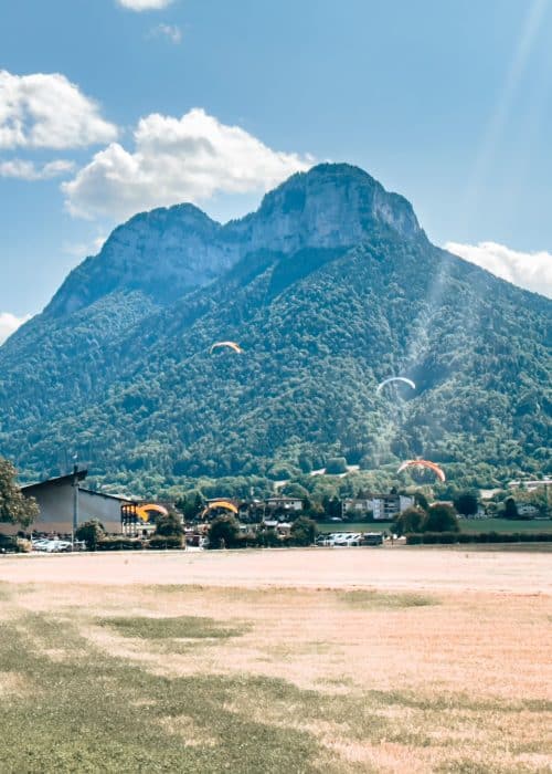 Paragliders landing in the mountainous countryside surrounding Lake Annecy, France