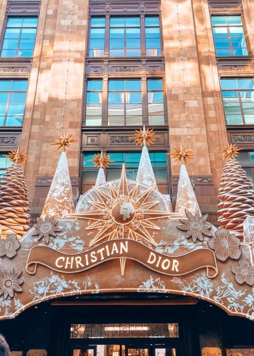 One of the entrances to Harrods decorated in gold with Christmas trees above the name Christian Dior, London