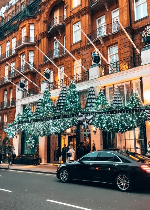 Elegant Christmas trees above the entrance to Claridge's with a luxury chauffeur car outside, London