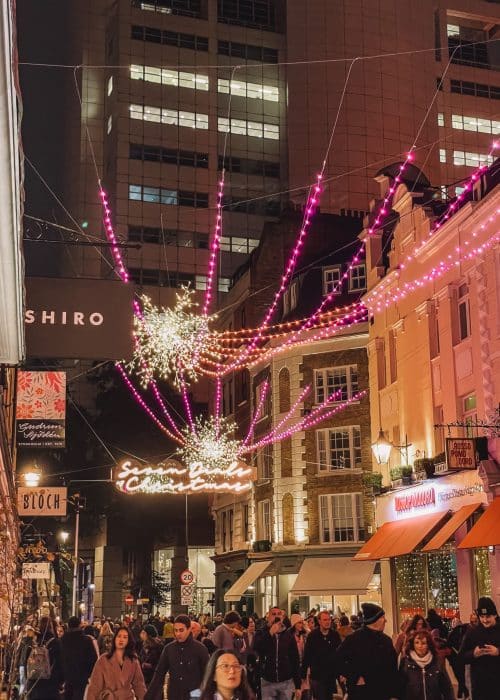 Pink and gold sparkling lights strung between the buildings in Seven Dials, Covent Garden at Christmas, London