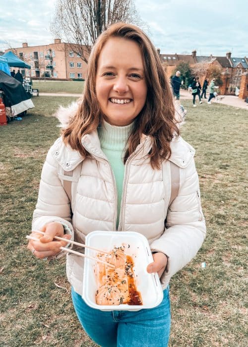 Helen holding a tray of street food dumplings from a market stall at Lloyd Park Market, Walthamstow, East London