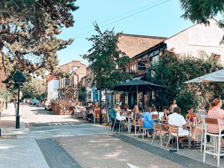 The quaint pedestrian street of Walthamstow Village with tables and chairs from the cafes in the street filled with people on a sunny day, London