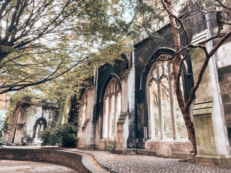 Blackened ruined walls of St Dunstan in the East Church surrounded by trees in the City of London