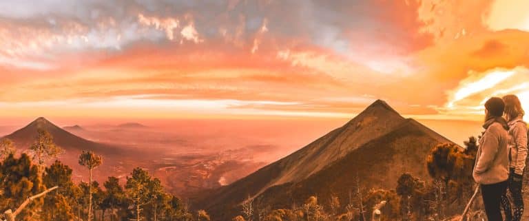 Gazing out over Volcan Fuego from base camp on Volcan Acatenango at sunset with the sky lit up in reds, oranges, blues and purples, Guatemala