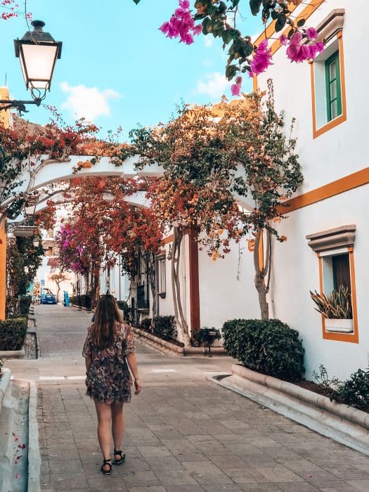Helen walking through the narrow streets of Puerto de Mogan with bright bougainvillea climbing the walls of the white-washed buildings, Gran Canaria
