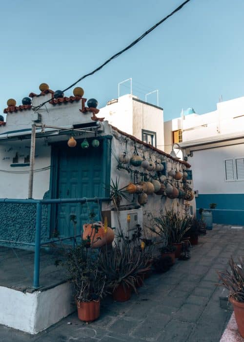 A narrow street with a blue and white house decorated with multi-coloured buoys, Puerto de las Nieves, one of the best places on your Gran Canaria itinerary, Canary Islands