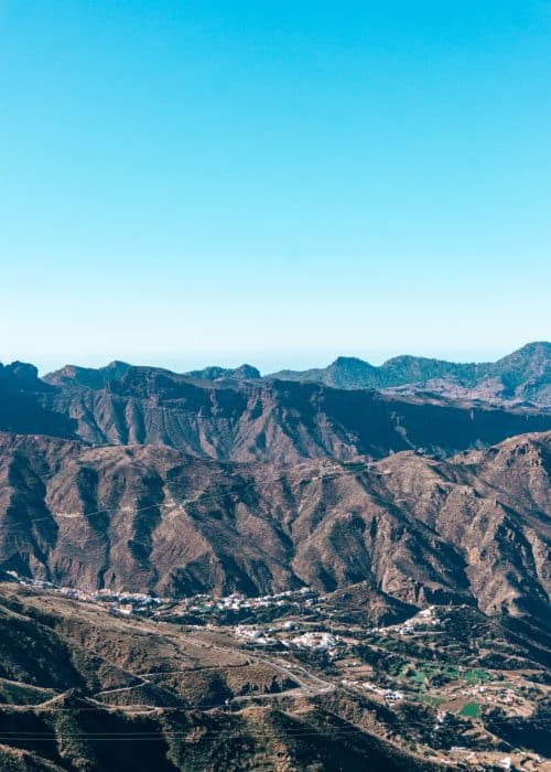 Looking over rugged volcanic landscapes with dramatic mountain peaks and a town nestled at the bottom, Tejeda, Gran Canaria
