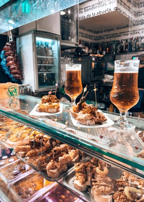 A tapas stall with two plates of food and two beers at Mercado del Puerto, Las Palmas, Gran Canaria, Spain