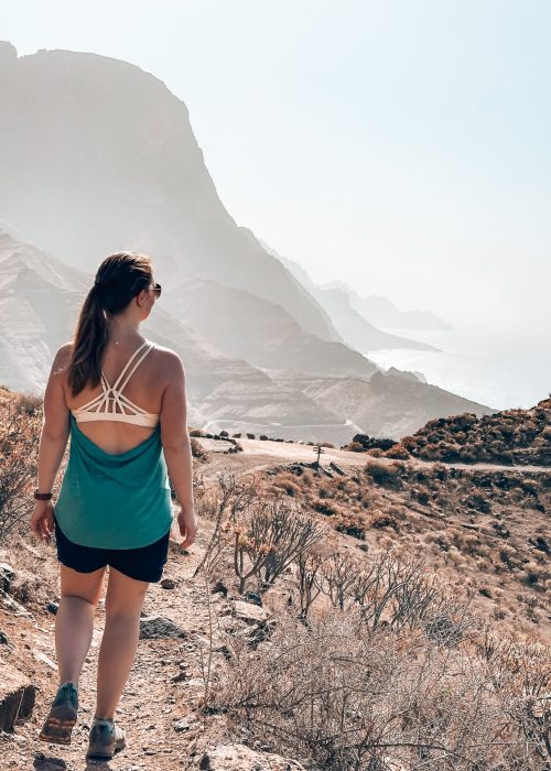 Helen hiking towards colossal cliffs plunging into the ocean in the Tamadaba National Park, one of the best places to visit on your Gran Canaria itinerary