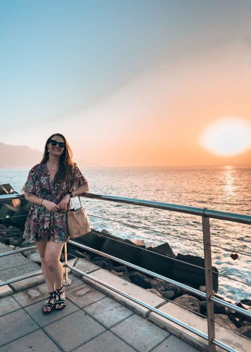 Helen standing on the promenade in Puerto de las Nieves with the sun setting over the ocean, Gran Canaria, Spain