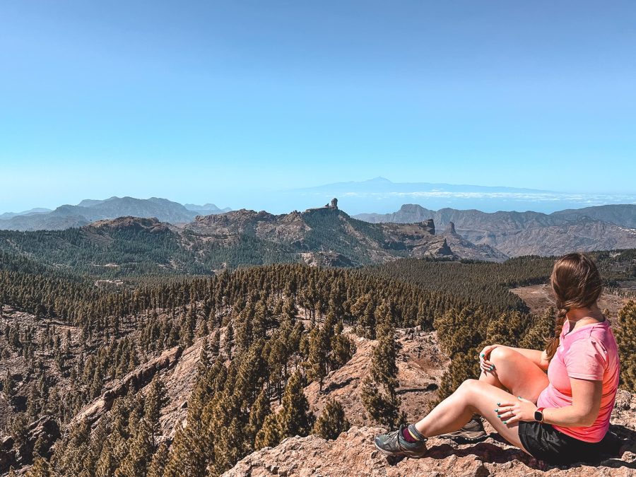 Helen sitting on the summit of Pico de las Nieves looking out to Roque Nublo and Mount Teide, Gran Canaria, Spain