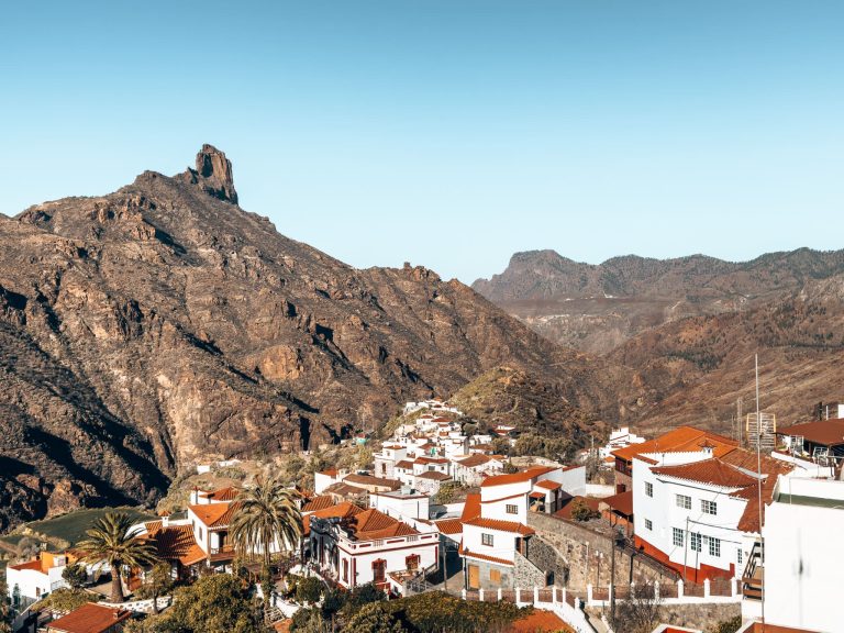 The view over white-washed houses with red roofs in the valley below Tejeda Town nestled underneath impressive rock formations