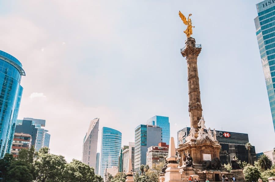 An imposing statue and numerous glitzy skyscrapers in the bustling Mexico City