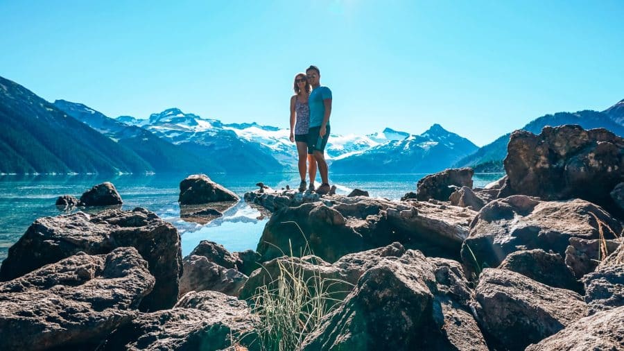 Helen and Andy stood on a rock at Garibaldi Lake Campsite with the lake and Sphinx Glacier behind, Garibaldi Provincial Park, Whistler