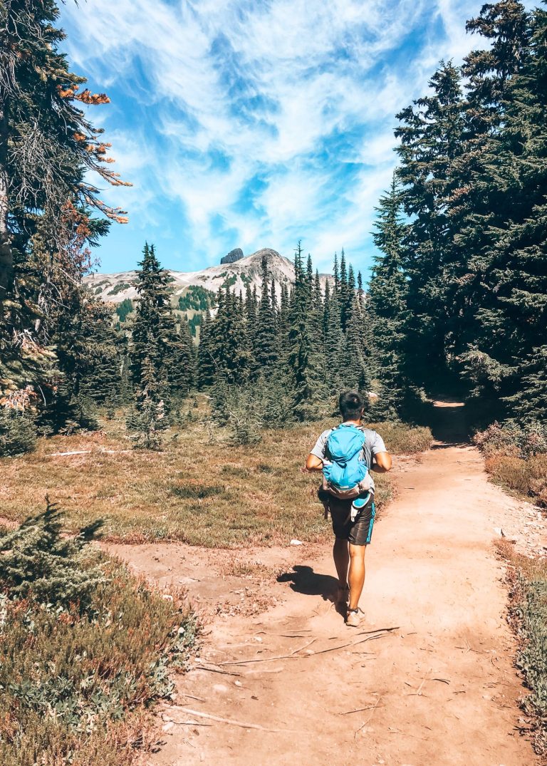 Andy hiking through a beautiful alpine meadow with the intimidating rock of Black Tusk looming above, Garibaldi Provincial Park