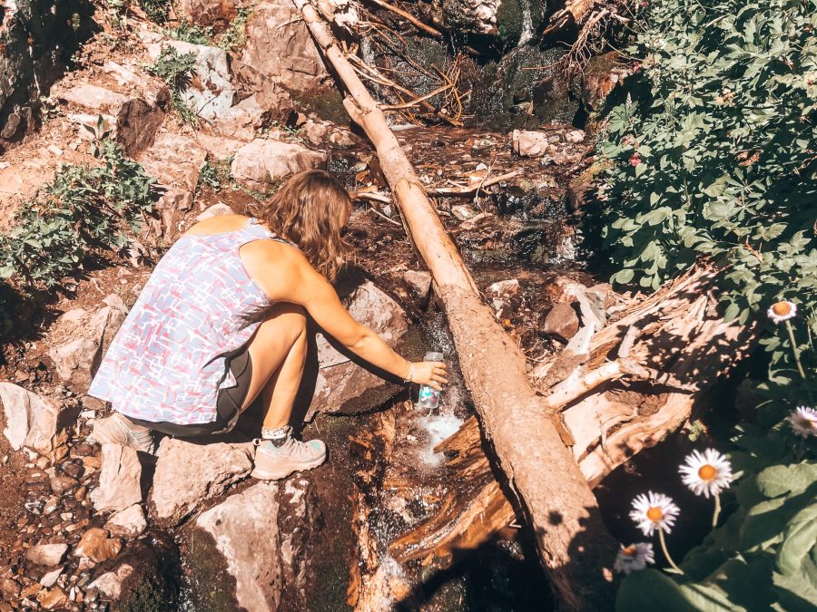 Helen collecting water from a stream in her bottle in Garibaldi Provincial Park, British Columbia, Canada