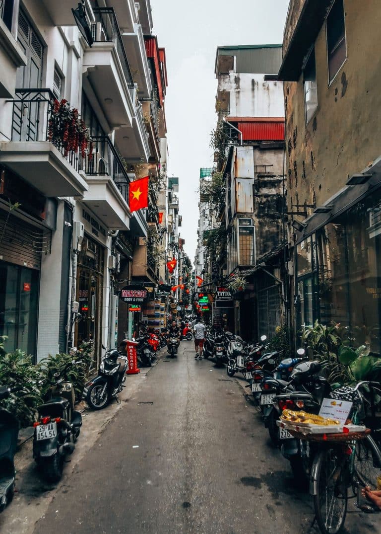 A narrow street lined with small shops and historical buildings in Hanoi Old Quarter, best of Vietnam