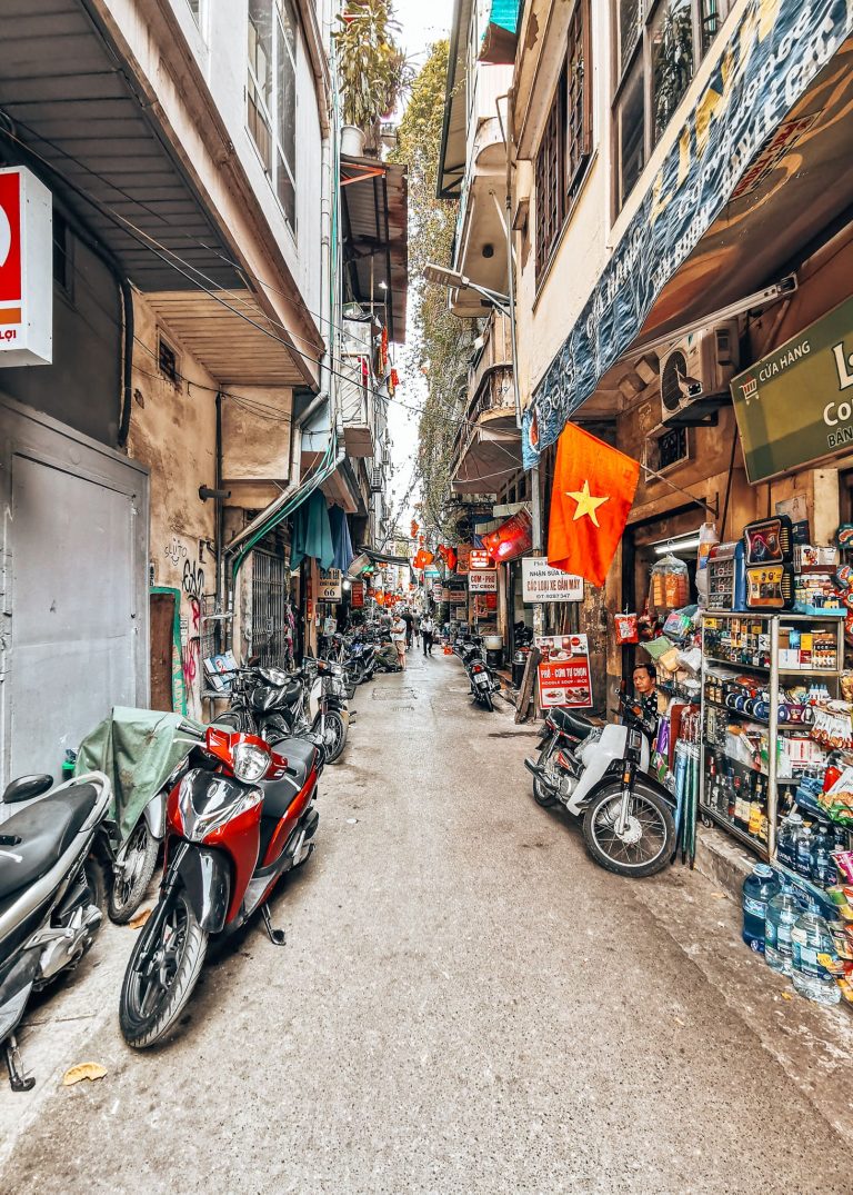 A narrow street lined with small shops and historical buildings in Hanoi Old Quarter, best of Vietnam