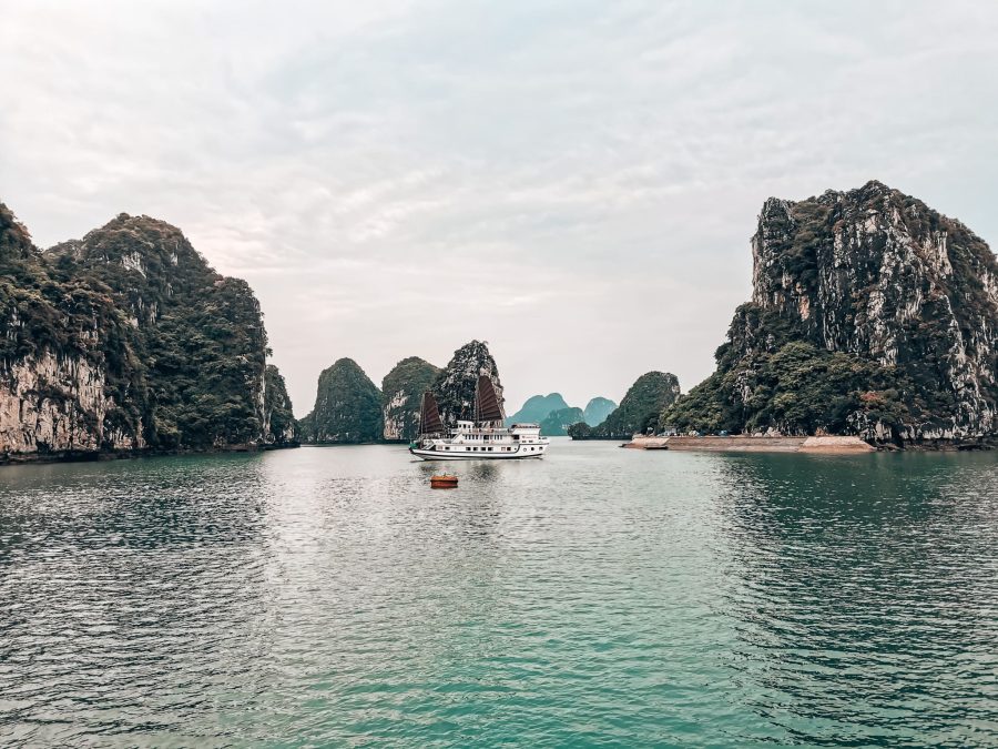 A cruise ship floating peacefully in between limestone karsts in the magnificent Lan Ha Bay, one of the most beautiful places to visit in Vietnam