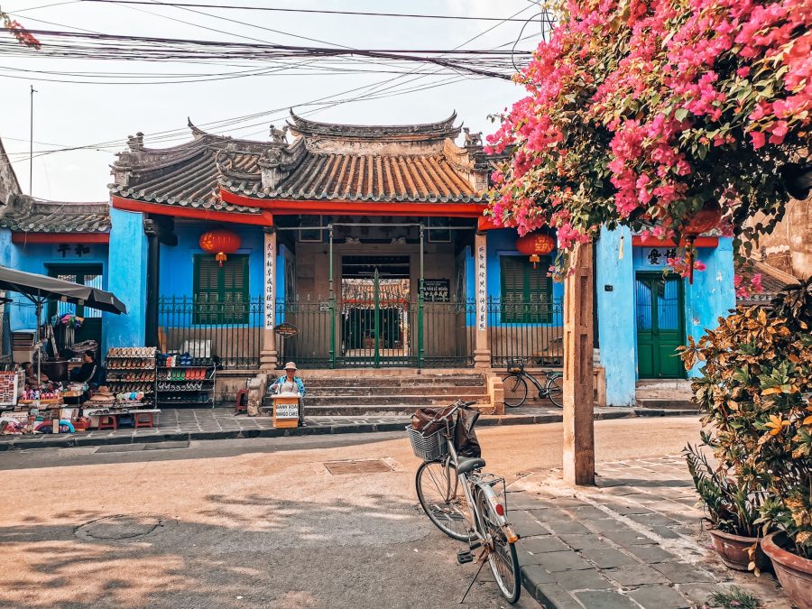 A vibrant blue historical building with a bike and pink flowers out the front of in Hoi An Old Town, best of Vietnam