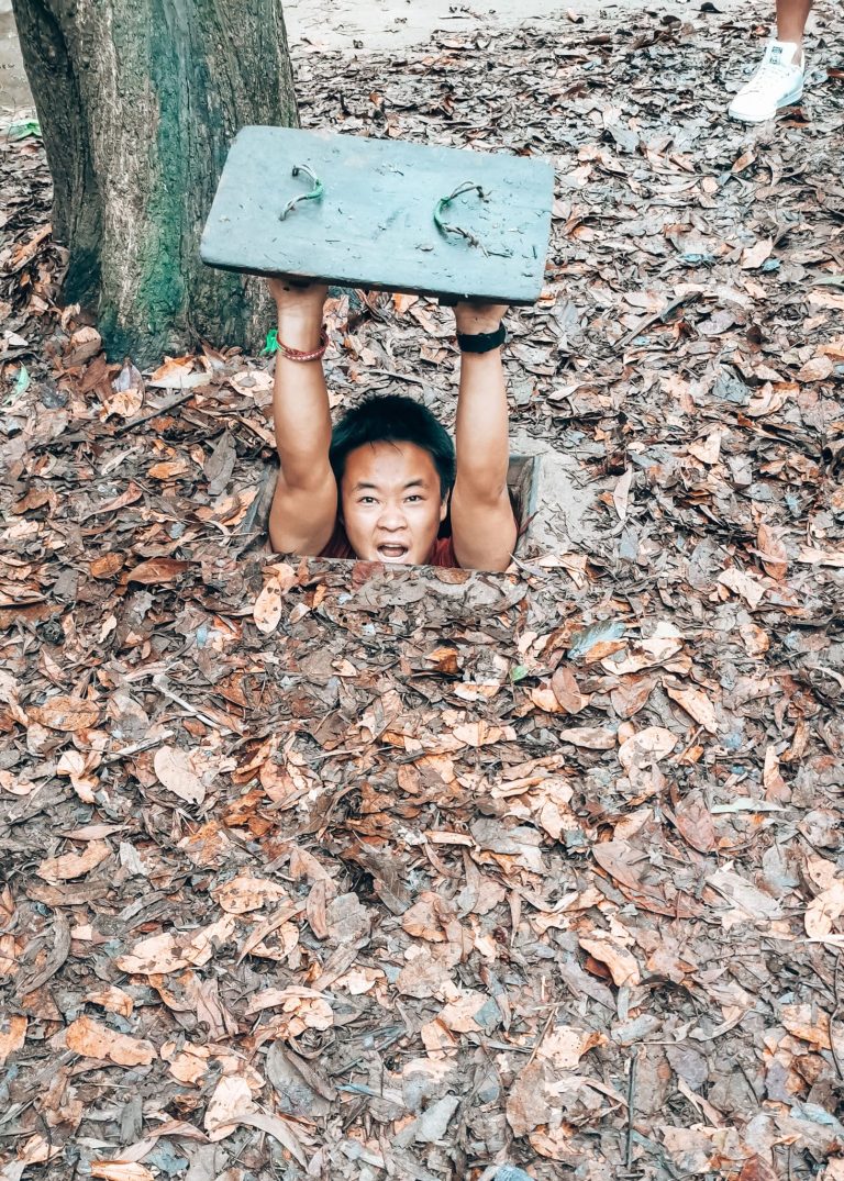 Andy in a small tunnel in the ground at the Cu Chi Tunnels, one of the best things to do in Vietnam, Ho Chi Minh City