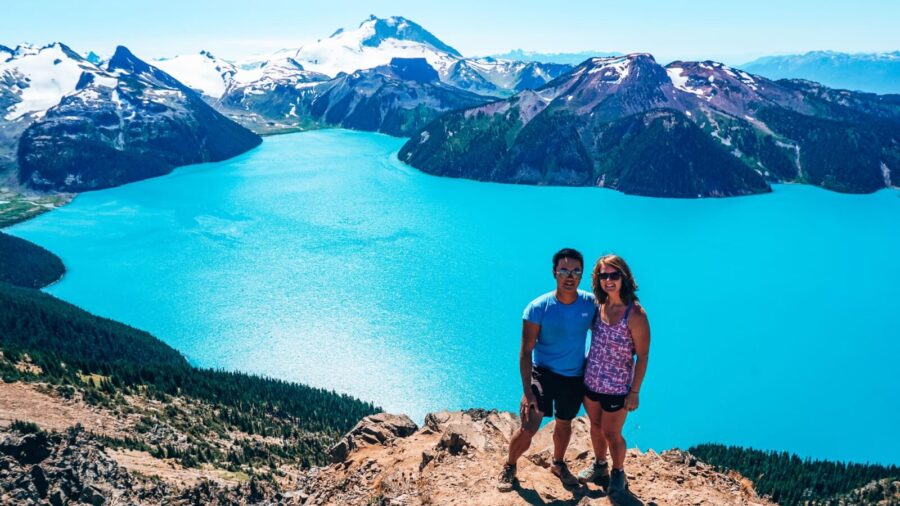 Helen and Andy stood at the top of Panorama Ridge with a deep blue Garibaldi Lake below, best hikes in Whistler