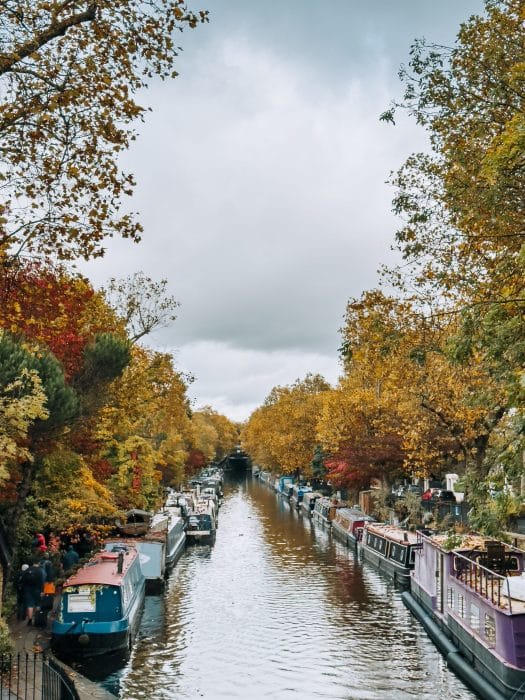 A canal full of colourful houseboats surrounded by autumnal trees, Little Venice, North London
