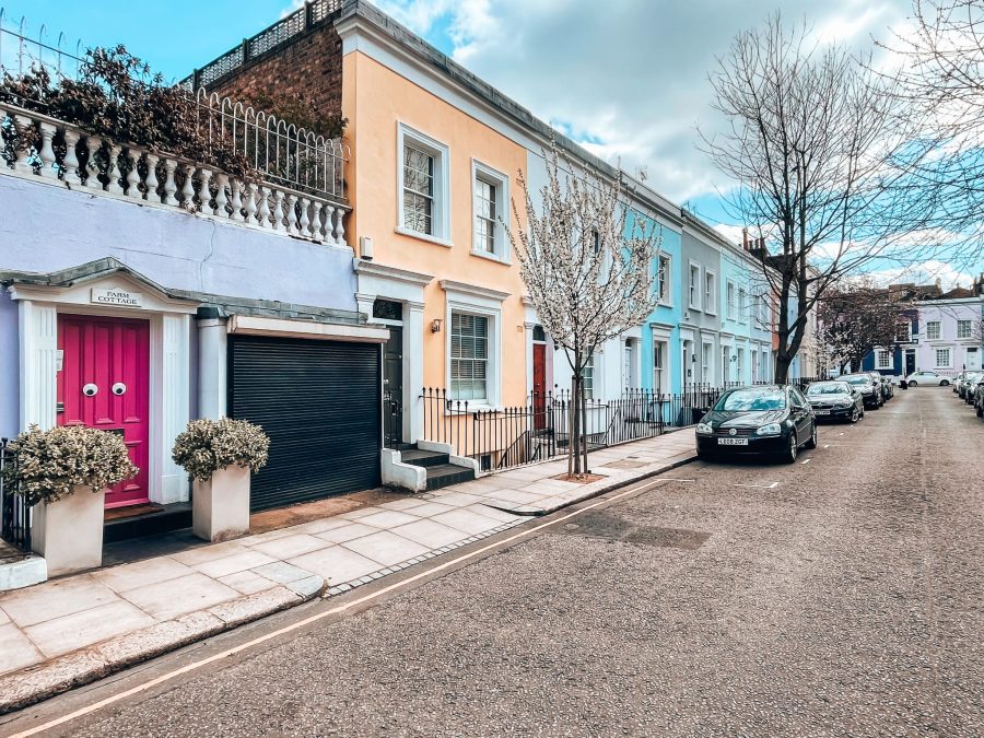 A row of vibrant coloured terrace houses with one with googly eyes on a bright pink front door, Farm Place, Prettiest Streets in London