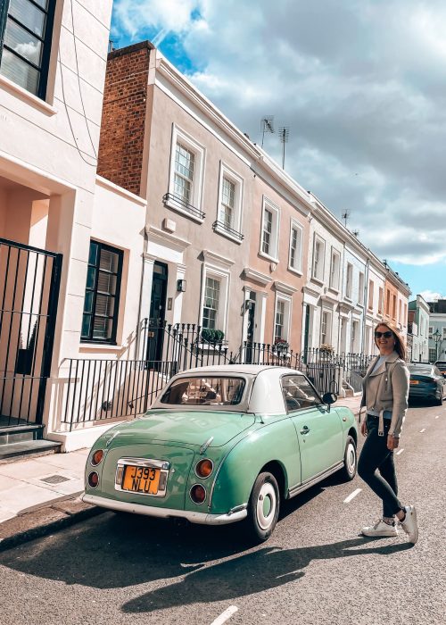 Helen and a green vintage car in front of a row of pastel-coloured houses on Callcott Street, one of the prettiest Streets in London