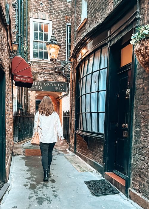 Helen walking through a narrow alley with bow-fronted cottages, Goodwin's Court, Covent Garden, London