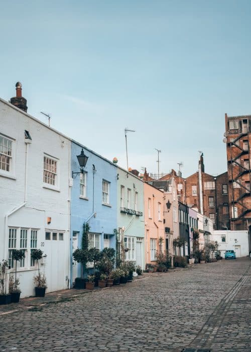 A row of blue, green and yellow terraced houses on a historical mews, Conduit Mews, London