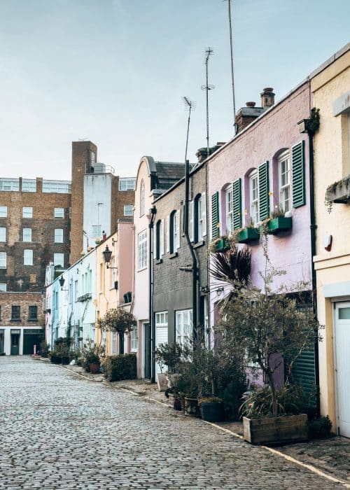 A row of purple, blue and yellow terraced houses on a historical mews, Conduit Mews, London