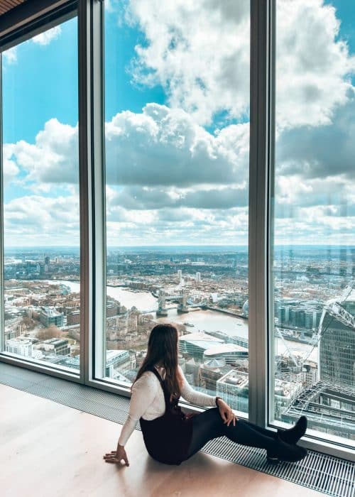 Helen sat on the floor by huge glass windows lookout to Tower Bridge from The Lookout, best views of London