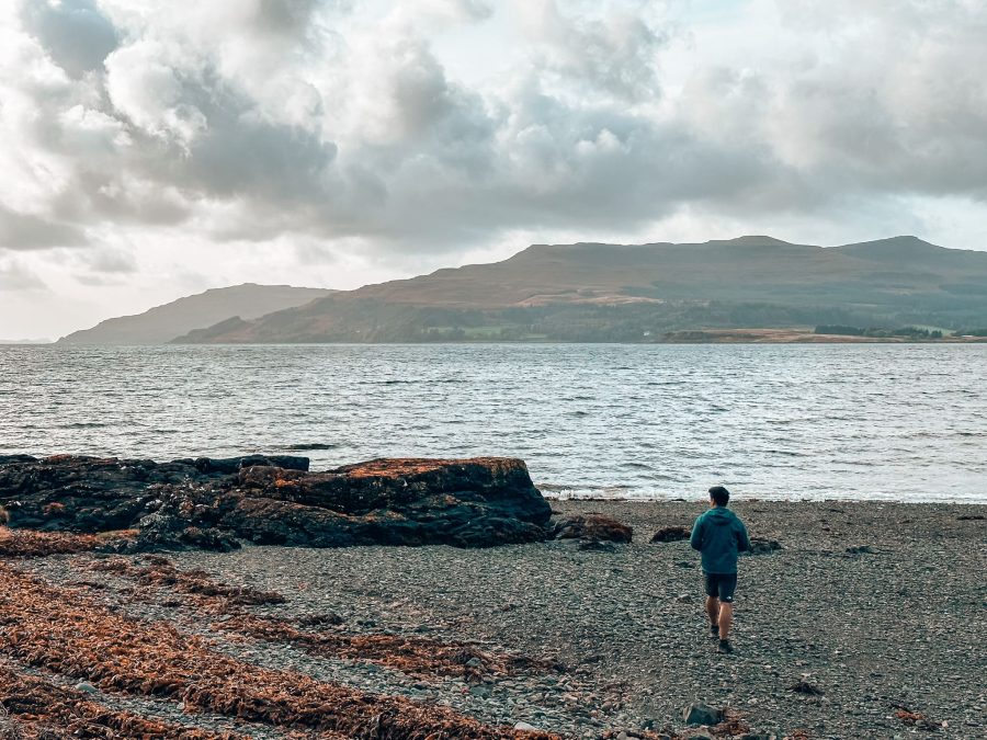 Andy walking on a pebbly beach overlooking Loch Scridain and the mountains behind, best things to do on the Isle of Mull