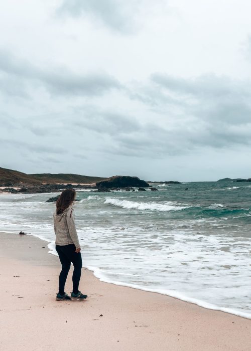 Helen stood on a white sand beach in front of the ocean on the Isle of Iona, Isle of Mull itinerary