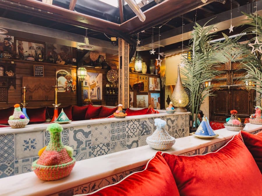 Red velvet cushions, colourful woven baskets and intricate lights in Oasis Lounge London, Moroccan restaurant in North West London